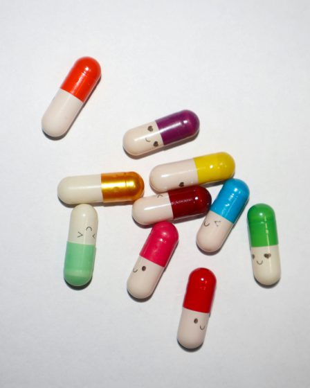 Mehrere bunte Medikamentenkapseln mit verschiedenen Farben liegen verstreut auf einem weißen Hintergrund
