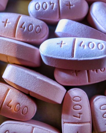 Nahaufnahme von rosafarbenen Tabletten mit der Prägung „400“ und einem Kreuzsymbol, die dicht nebeneinander liegen